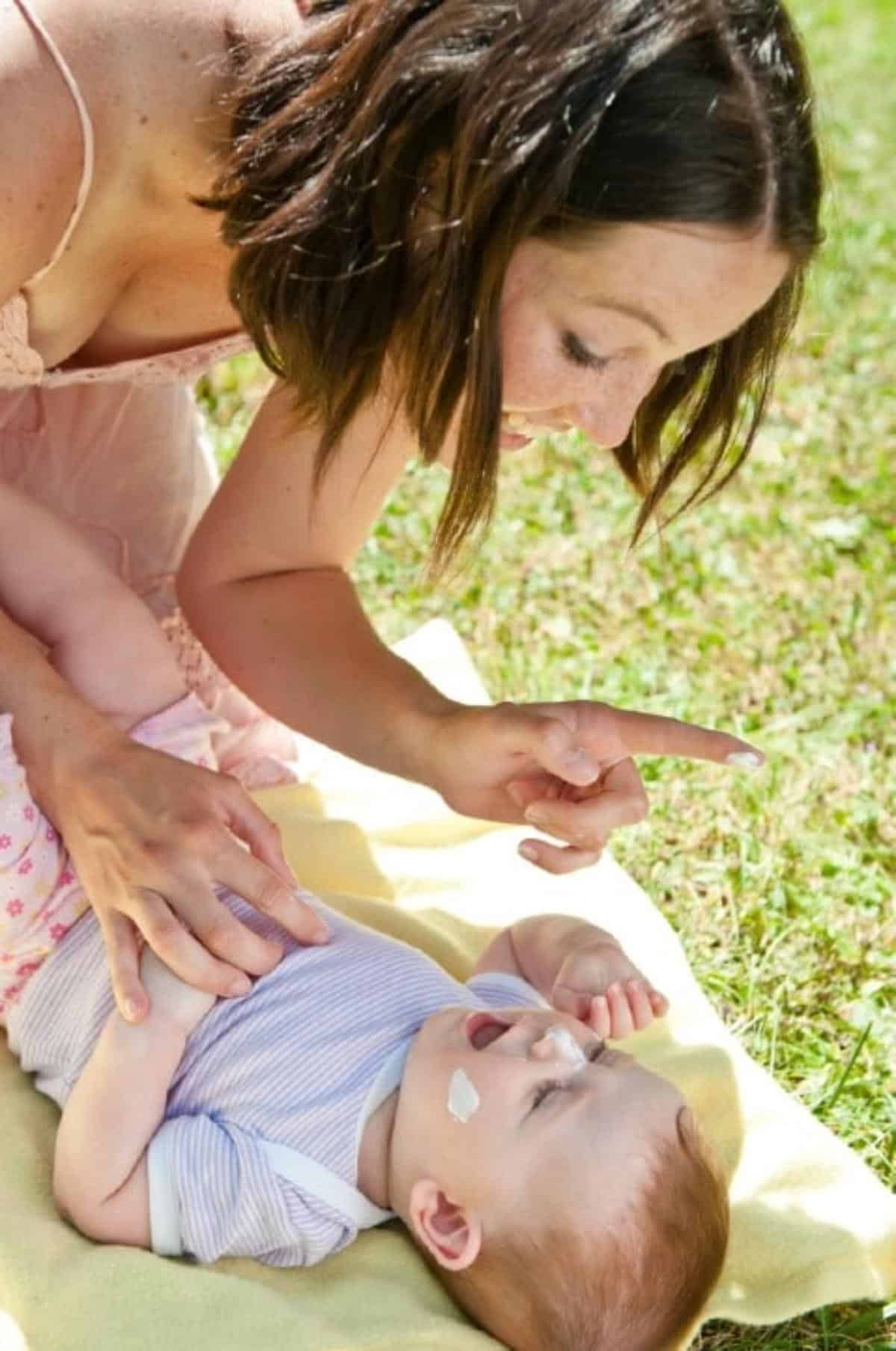 Mother sunscreens her baby,
