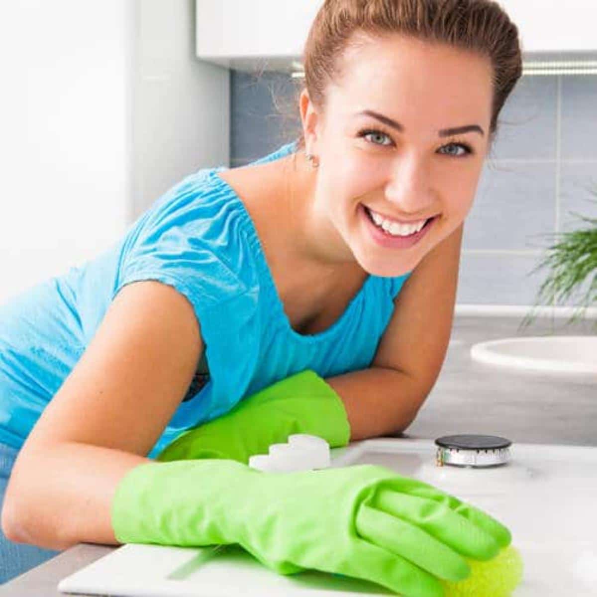 A smiling woman cleaning a desk.
