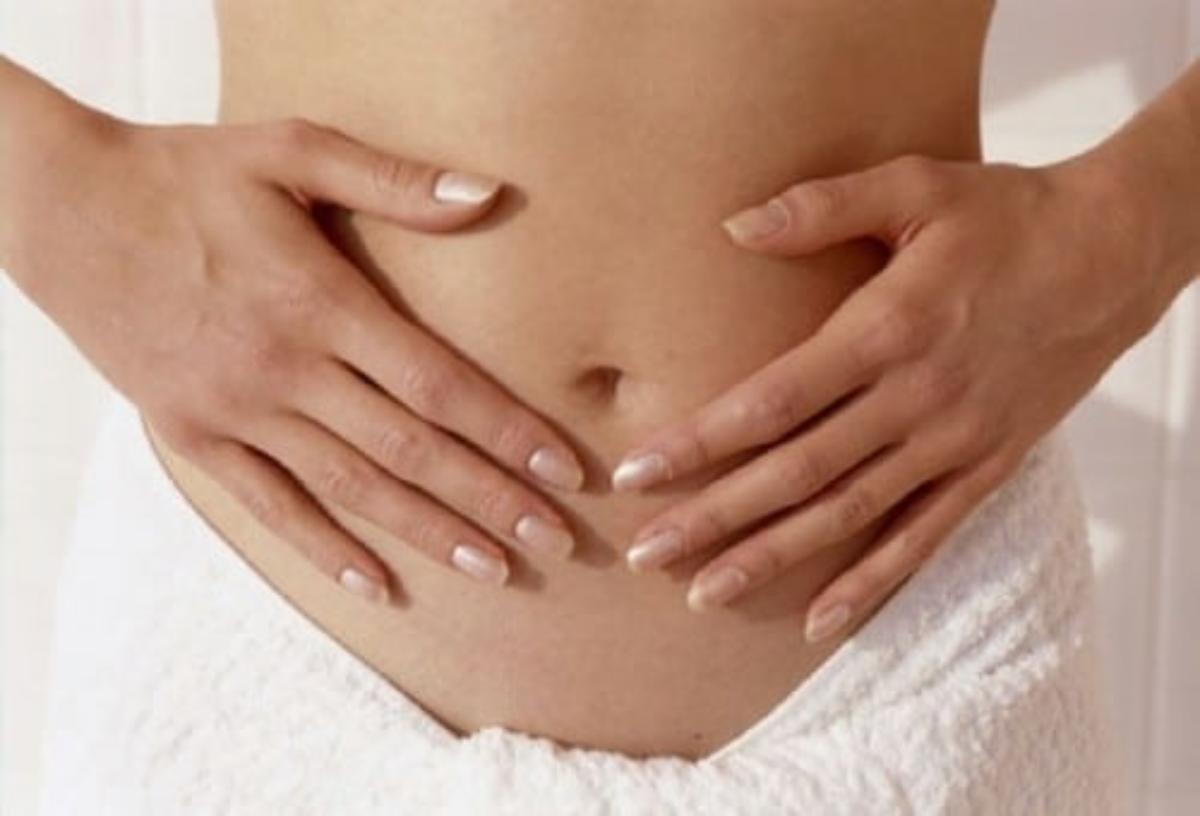 A woman with hands on her stomach area.