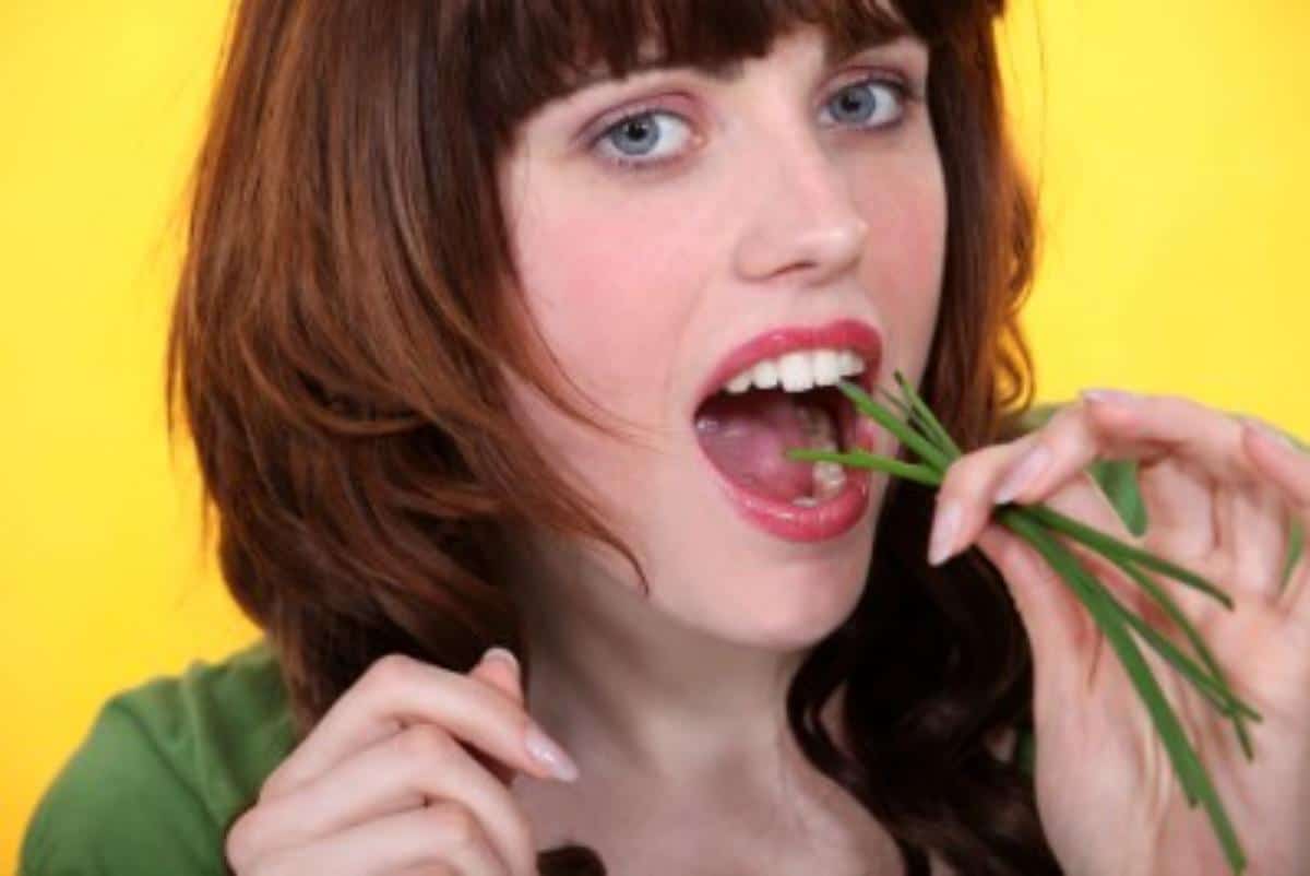 A woman is eating herbs