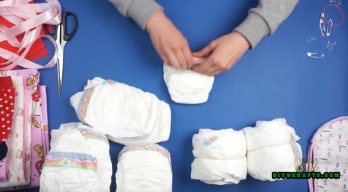 Roll 4 diapers into one another to create a wheel. Do this 6 times so you have 6 wheels.