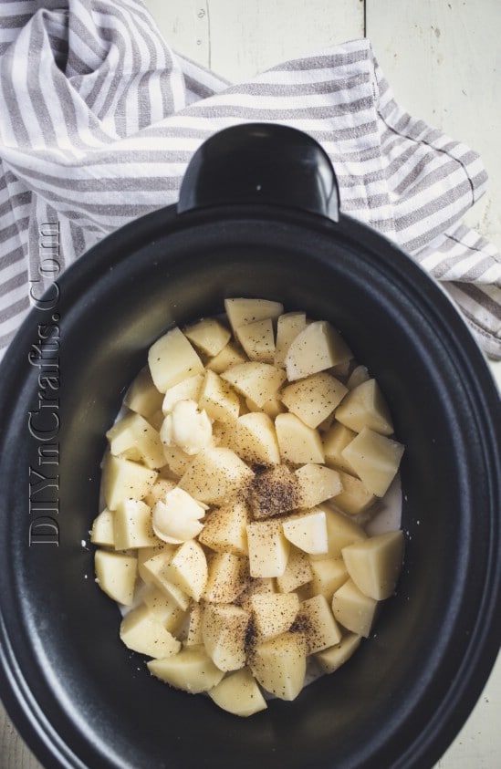 Putting the cubed potatoes into the slow cooker.