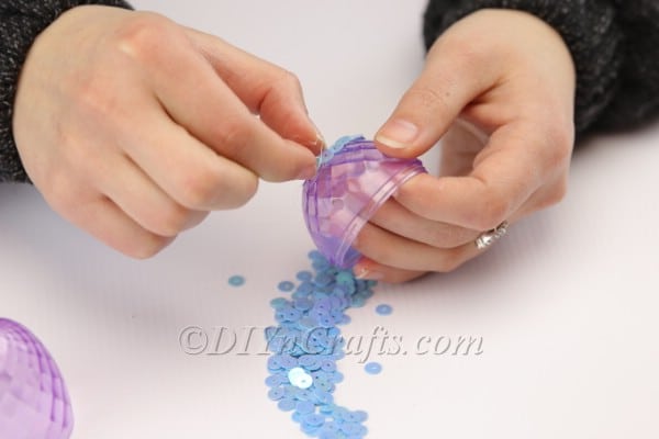 Manually placing sequins to decorate the plastic egg.
