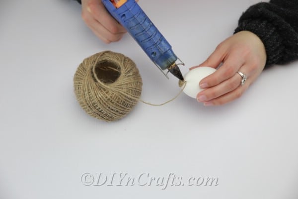 Applying hot glue to the top of the egg.