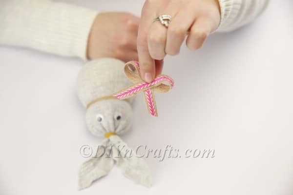 Attaching a cute bow to the bunny's neck.