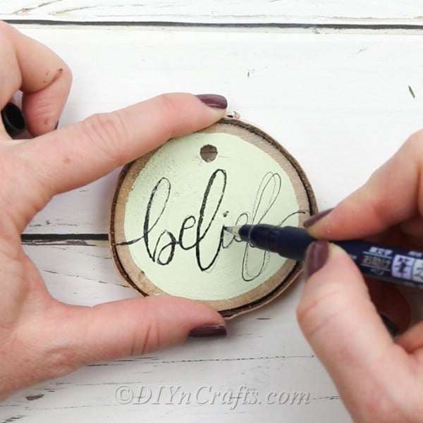 Use marker to trace over pencil writing on wood slices 