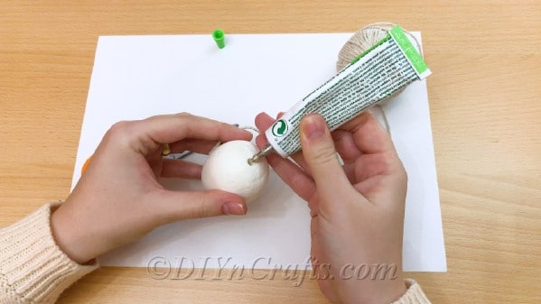 Place glue on the bottom of the egg to hold twine