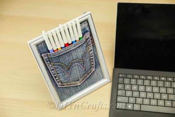 Pen pocket in a frame next to a laptop