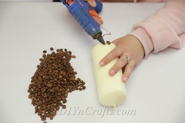 Adding coffee beans to a large pillar candle