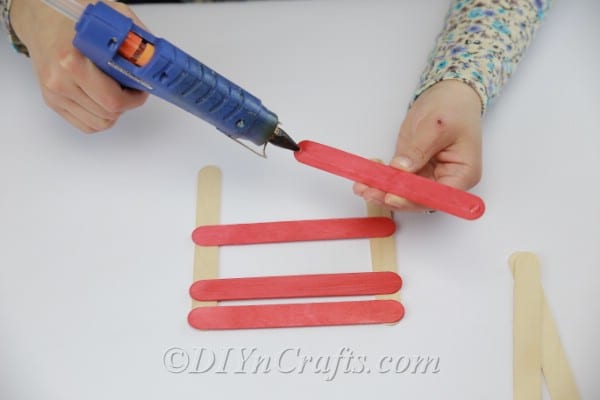 Adding hot glue to colored popsicle sticks