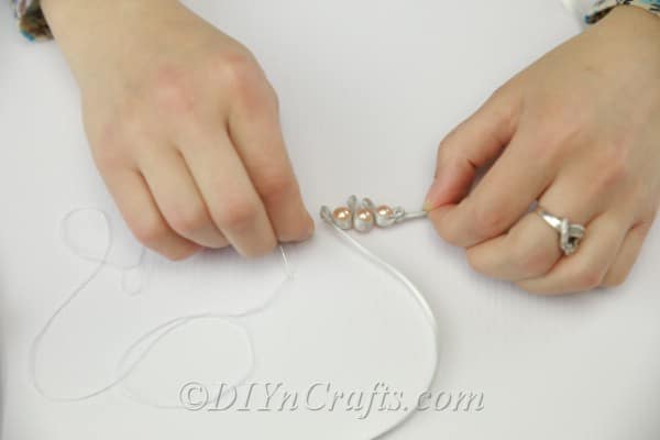 Sewing pearls into the satin ribbon