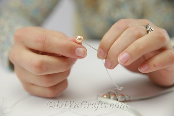 Sewing a pearl onto a satin bracelet