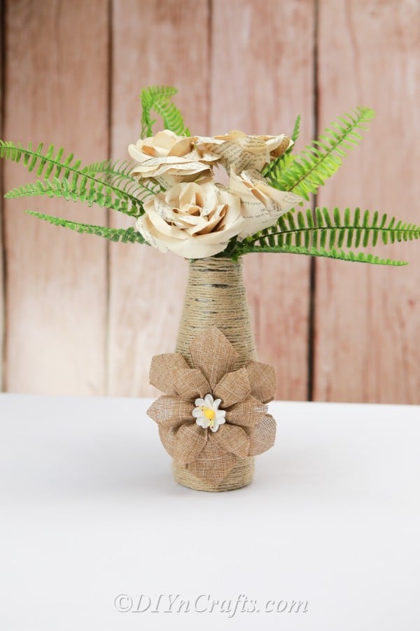 Rope covered bottle with paper flowers close up