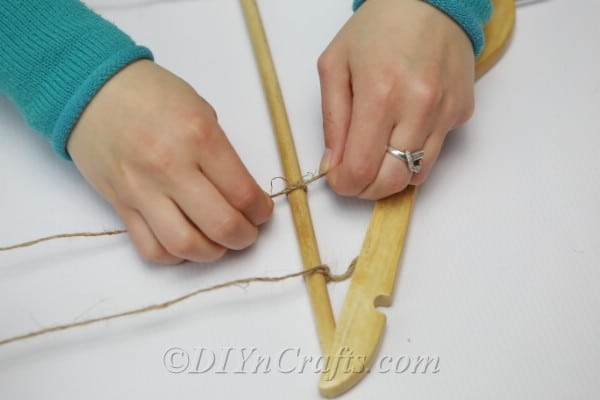 Tying twine onto wooden clothes hanger