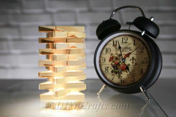 Clothespin lamp beside an alarm clock