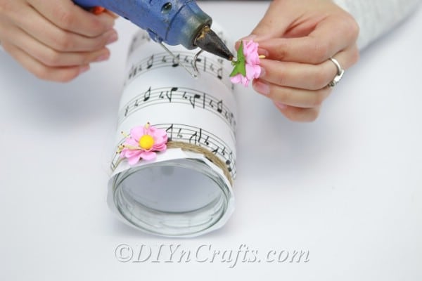 Adding artificial flowers to decorate a music sheet jar