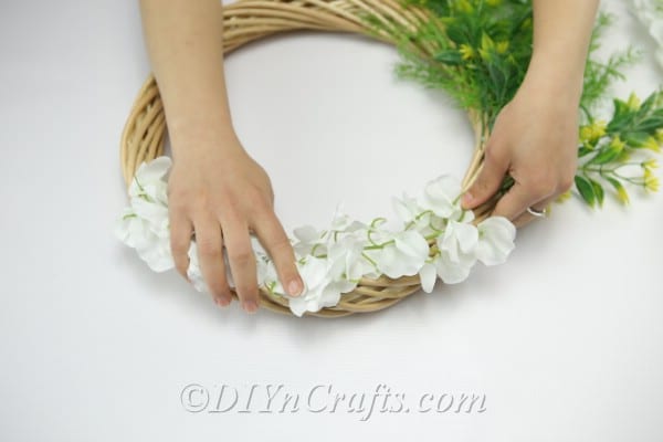 Arrange the flowers on the top part of the wreath.