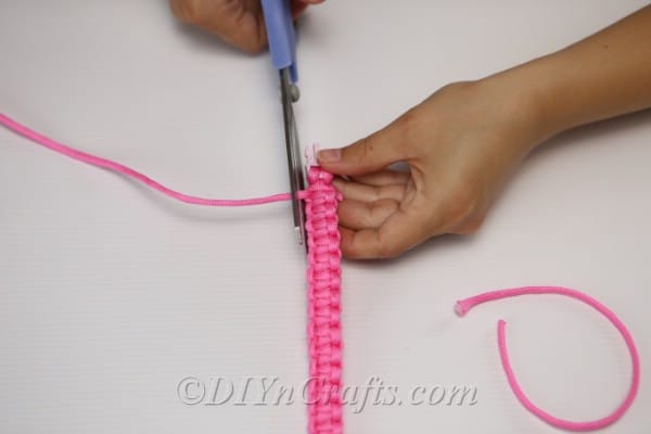 Trimming the ends of the thread from the square knot bracelet