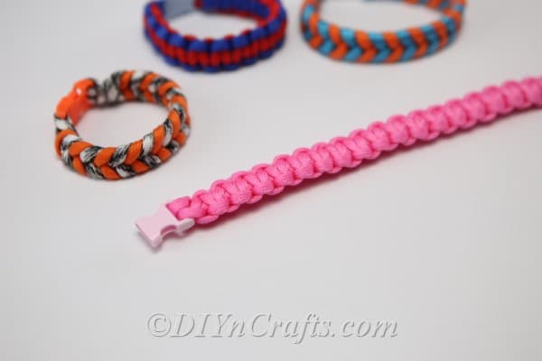 Picture of open square knot bracelet alongside 3 other paracord bracelets in various colors