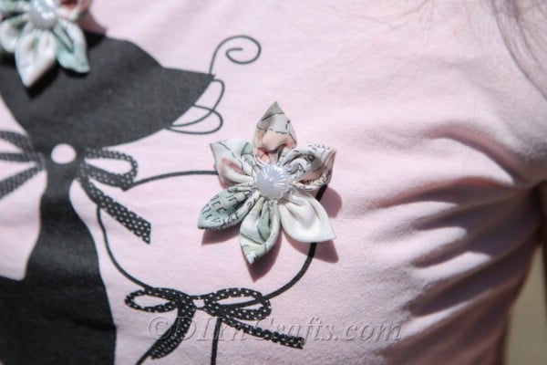 Une fleur en tissu épinglée à un t-shirt.