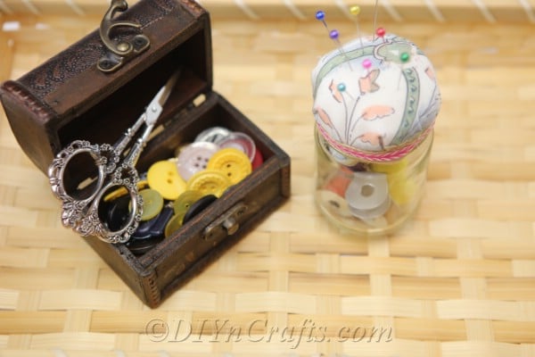 A completed pincushion jar with additional sewing supplies in a basket.