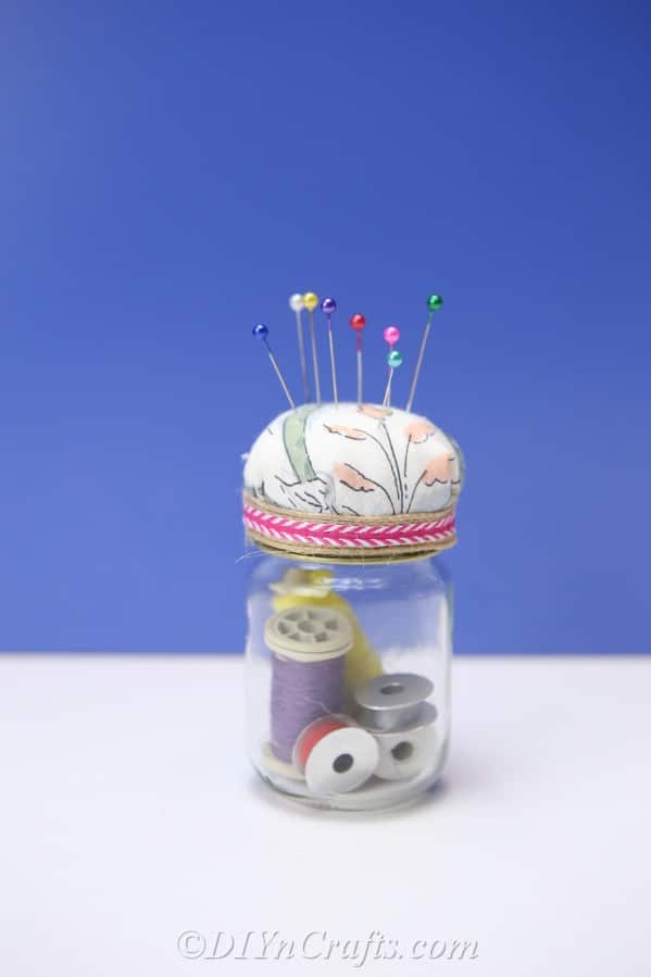 A completed pincushion jar against a blue backdrop.