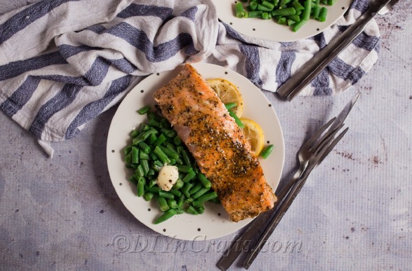Overhead picture of a piece of honey baked salmon on a white plate with gray napkin in background