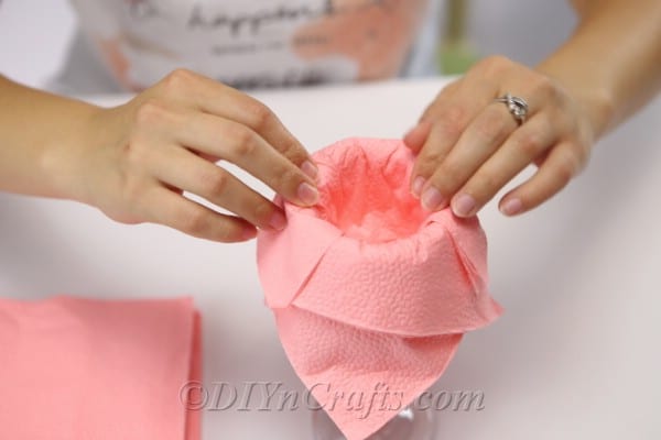 Overlapping pink napkins on edge of glass during how to fold napkins tutorial