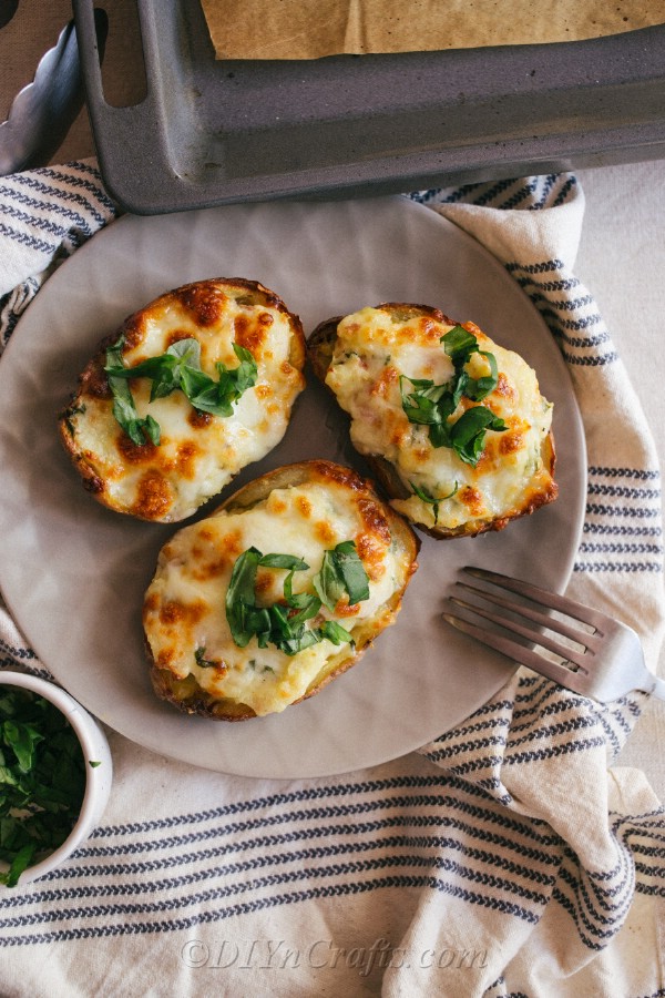 An overhead picture of loaded potato skins sitting on a plate with a fork on the side