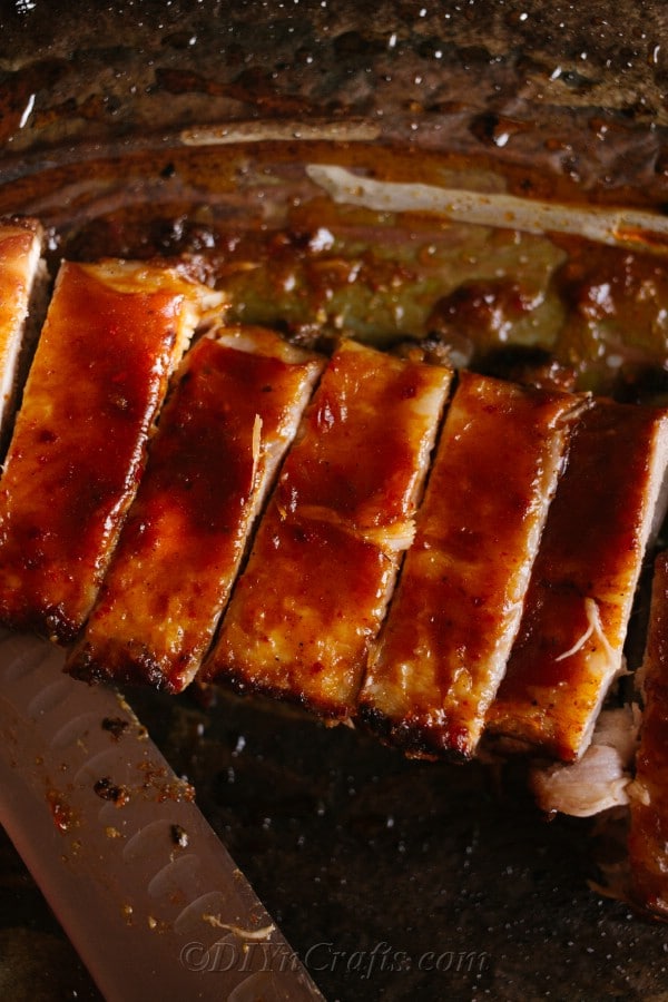 Baking sheet covered with bbq oven baked ribs sliced and ready to serve