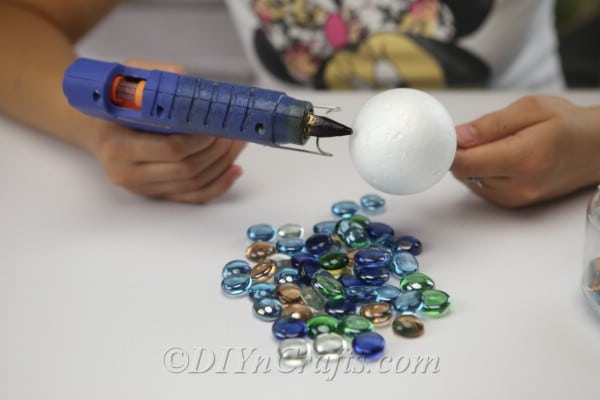 Begin gluing glass nuggets to the ball.
