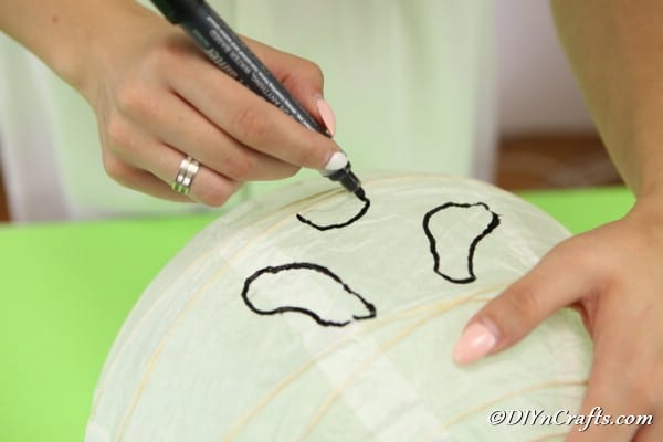 Drawing a face on the ghost paper lanterns with a marker