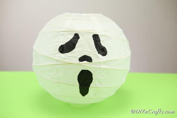 A completed ghost paper lantern sitting on a green surface