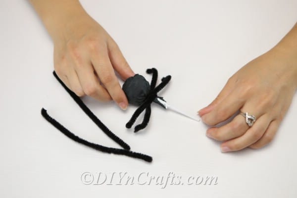Twisting pipe cleaners around lollipop to create legs on spider craft
