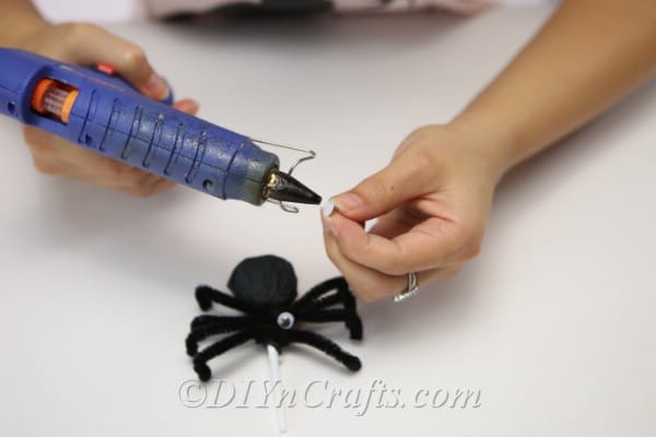 Gluing eyes on spider craft Halloween lollipop