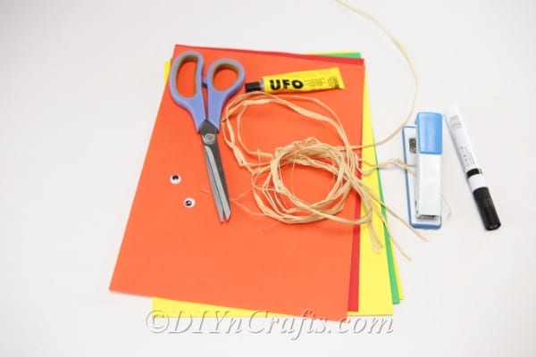 Supplies needed for making a paper scarecrow craft sitting on a white surface