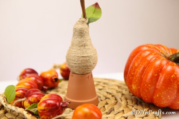 A wrapped pear fruit decoration sitting on top of a small terra cotta planter
