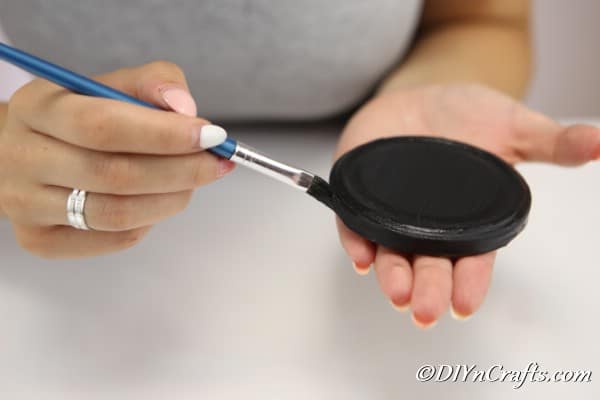 Painting the top of the mason jar lid with black paint