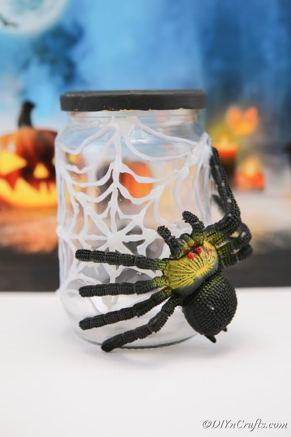 Completed halloween spider jar sitting on white surface with blue halloween themed background