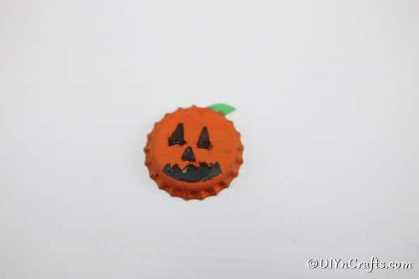 A completed orange pumpkin fun magnet made from bottle caps