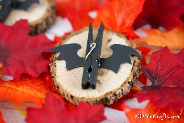 A completed clothespin bat sitting on a wooden stump