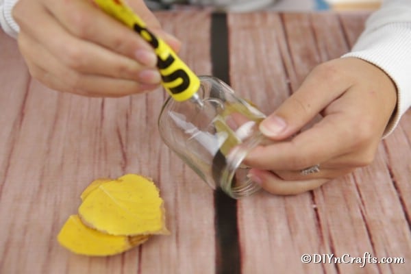 Gluing leaves onto glass jar for mason jar lantern crafts