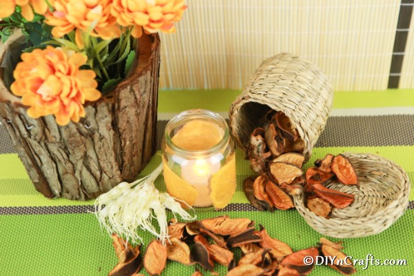 A fall themed display on green cloth with glass jar candle lantern in center