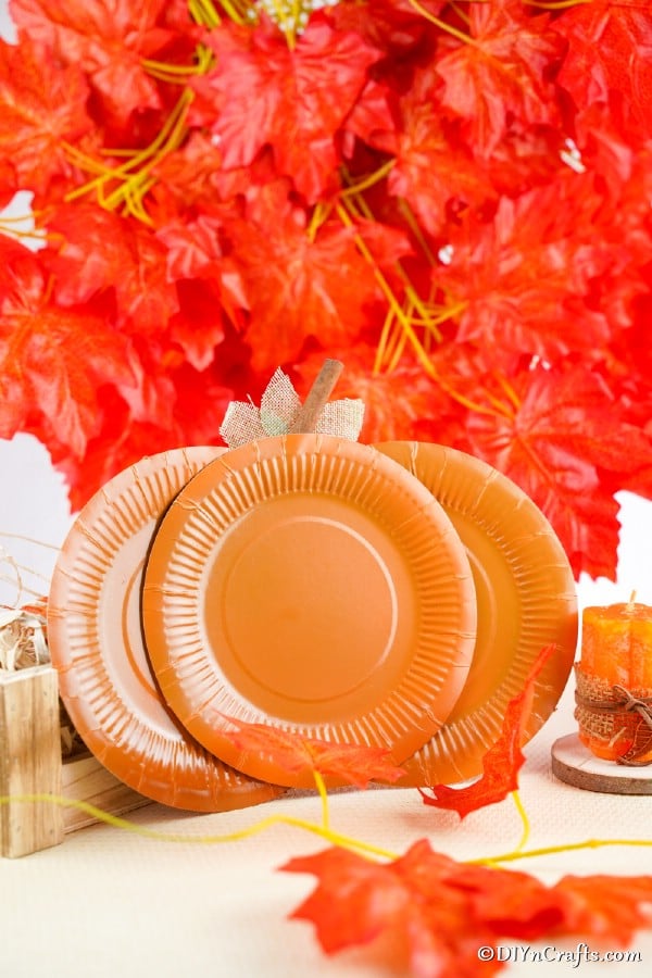 A paper pumpkin craft leaned against a wall of fake fall leaves