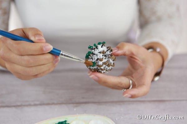 Painting the piece of a pine cone ornament green