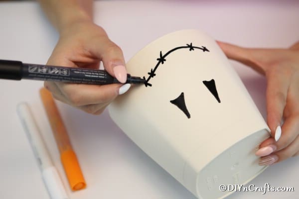 Drawing a face on the clay pot to create a scarecrow