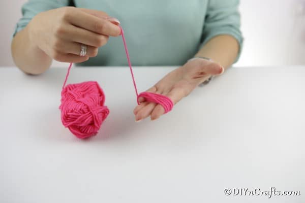 Wrapping yarn around your palm to create a yarn pom poms flower