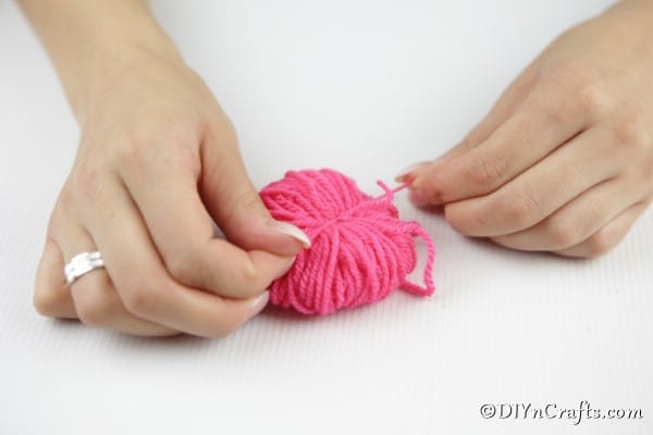 Tying yarn in the middle to create pom pom ball