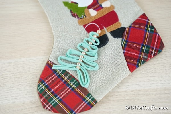 A ribbon and peral handmade Christmas ornaments idea laying on a Christmas stocking