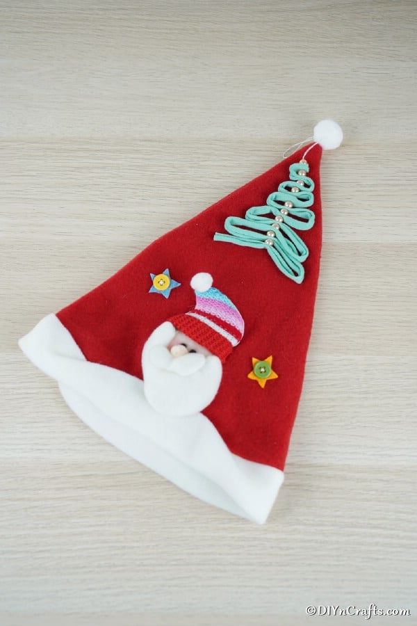 A pearl and ribbon christmas tree ornament laying on a santa hat